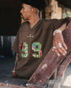 model wearing embroidered football jersey in brown facing left 