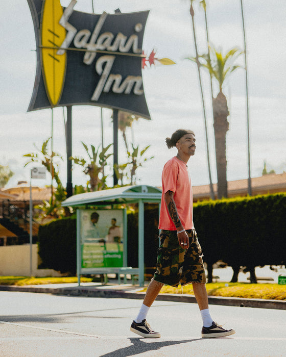 model walking across street in vintage red logo tshirt and distressed print shorts